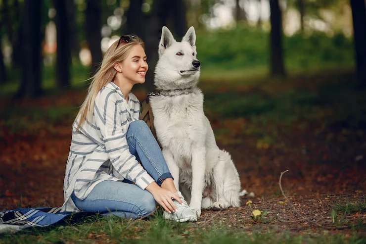 Woman sitting beside a white dog.