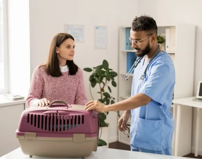 Veterinarian assisting pet owner with carrier.